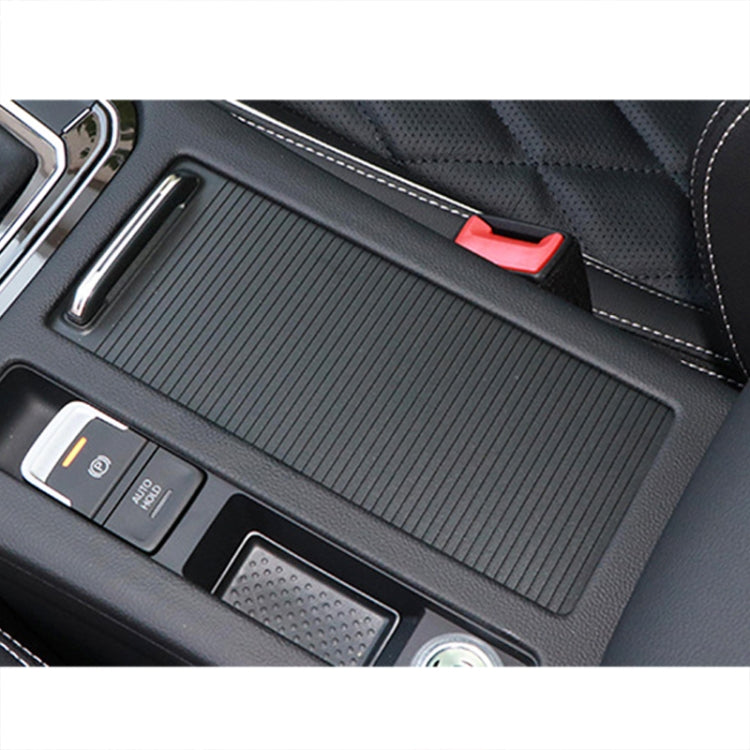 Installed black textured armrest box cover with chrome-edged pull slot on console