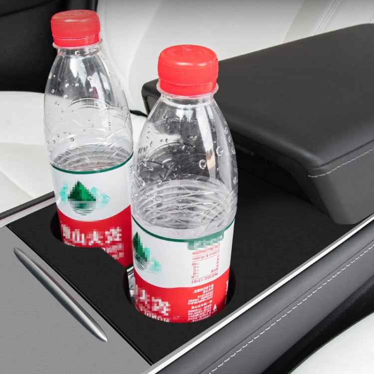 Black cup holder pad holding two water bottles upright in car center console
