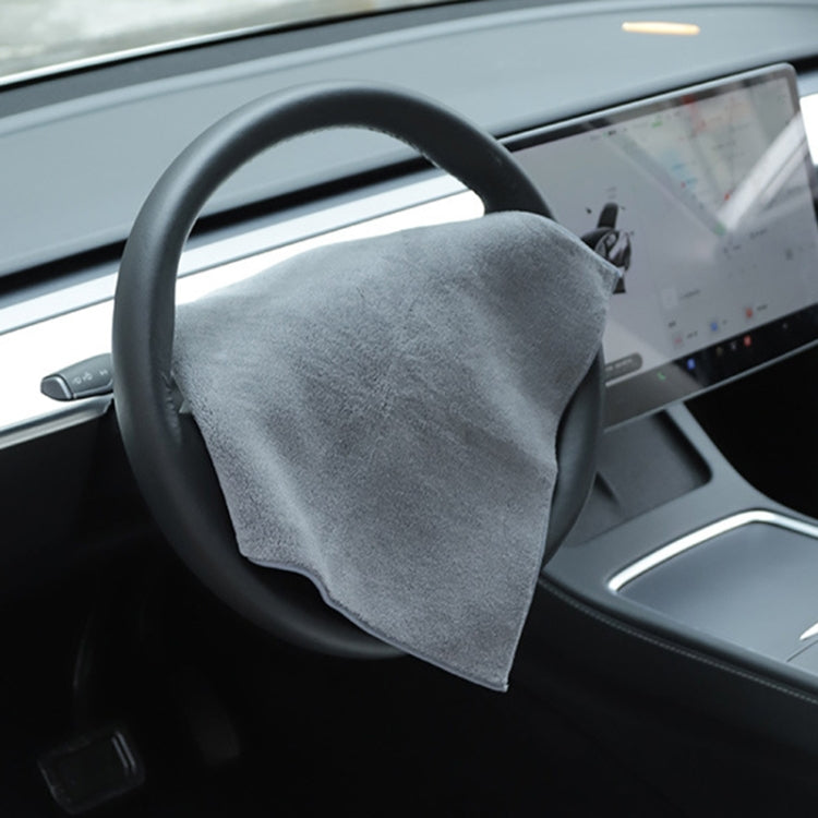 Gray microfiber car cleaning towel draped over steering wheel, no logo.