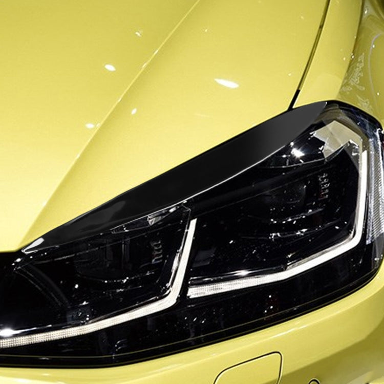 Close-up of black headlight eyebrow stickers on a car headlamp with glossy trim.