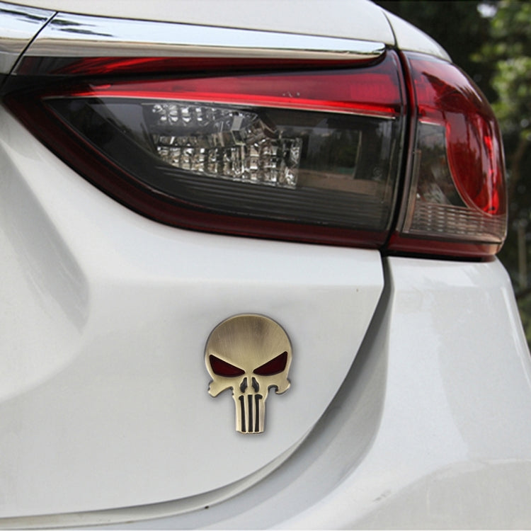 Gold metal skull car sticker with red eyes on a white rear panel
