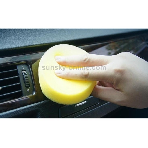 Yellow foam cleaning sponge used on a car dashboard near air vents