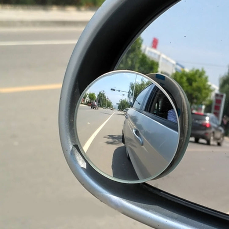 Circular wide-angle blind-spot mirror attached to car side window, street reflection