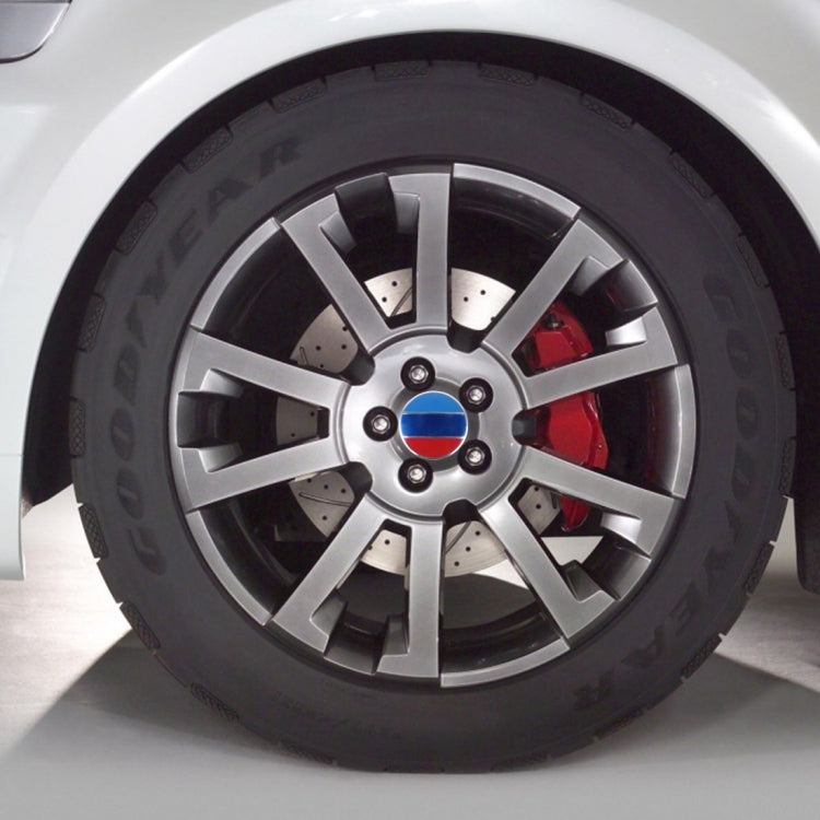 Car wheel with round metal hub center badge featuring blue, white, and red flag colors