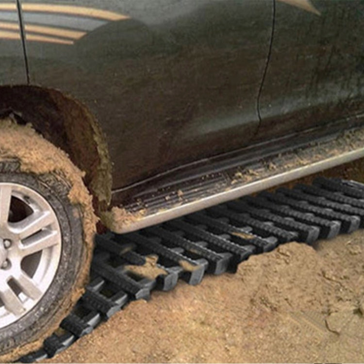 Car wheel partly on black rubber traction rescue track for grip on muddy ground
