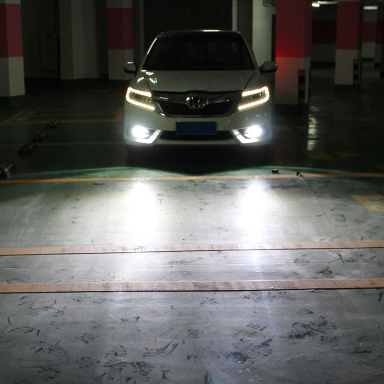 Car in indoor garage with fog lights on, showing bright white beam