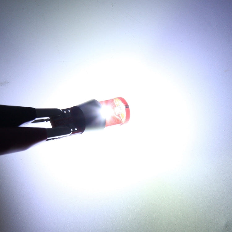 Lit T10 LED bulb producing bright white light, red base and white metal body visible