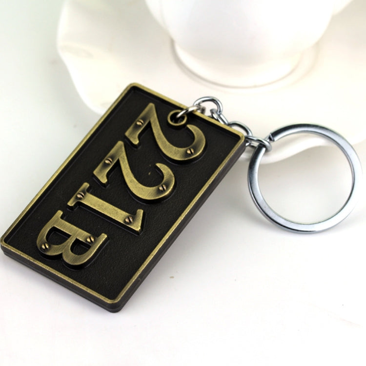 Gold-tone metal keychain with 221B and Sherlock-style engraving and split-ring