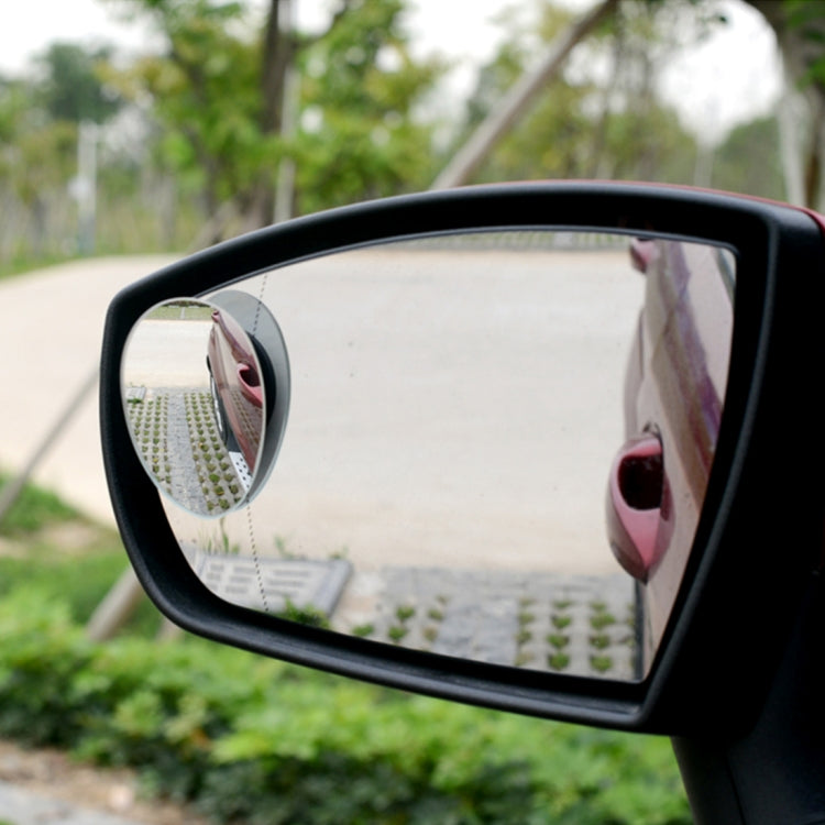 Mounted black oval blind spot mirror on car, reflecting the road behind