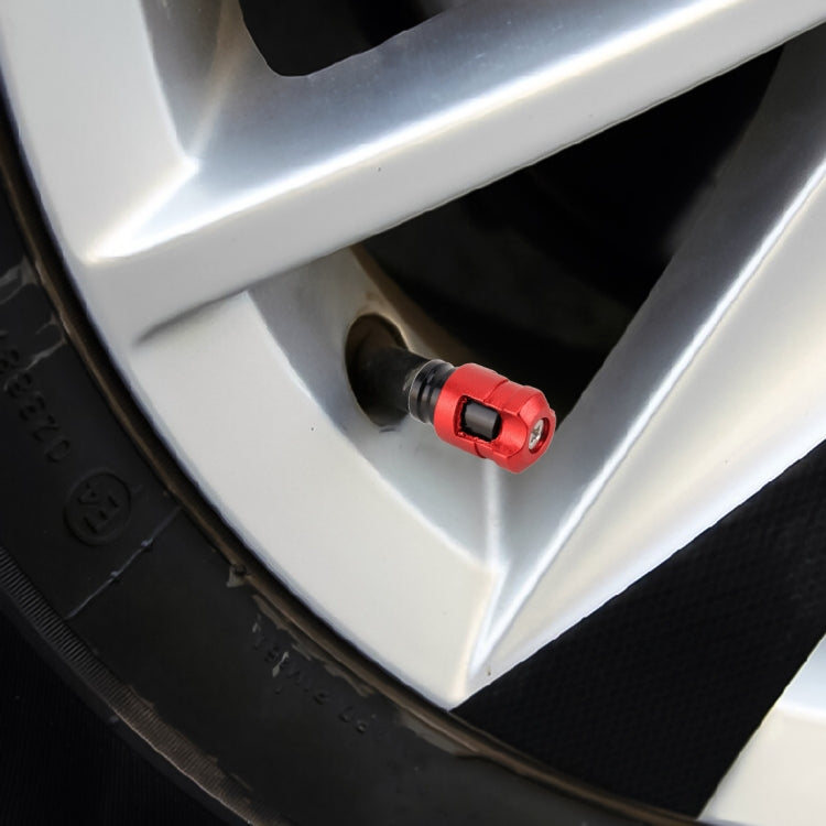 Red tire valve cap installed on a wheel rim valve stem