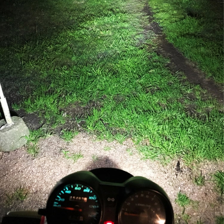 Motorcycle LED headlight lighting a grass-and-gravel path ahead with a bright beam