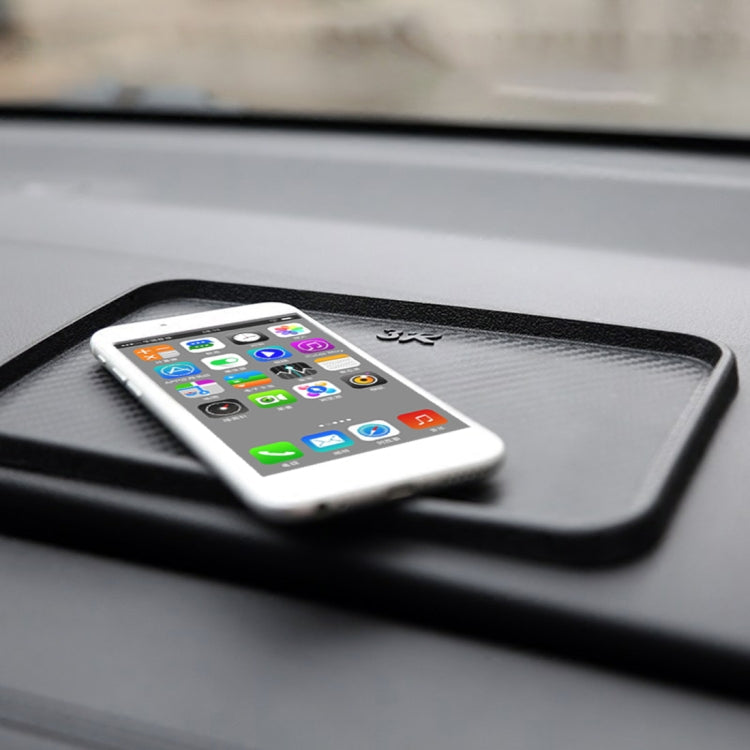 Black anti-slip rubber car mat with textured top and resting smartphone