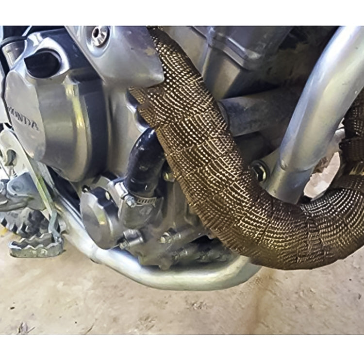 Gold-toned exhaust heat shield wrap installed on a curved motorcycle exhaust pipe