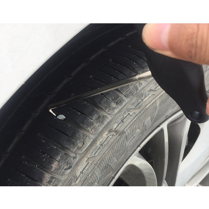 Black-handled trim tool inserted beside tire and wheel well edge