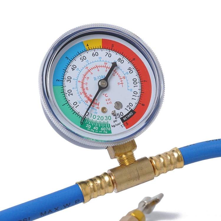 Refrigerant pressure gauge dial close-up with brass connector on blue hose