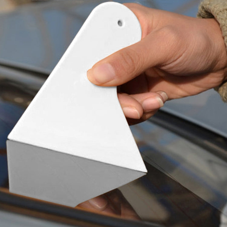 Hand holding white triangular window film scraper tool for car glass, hanging hole