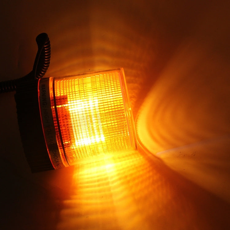 Glowing amber strobe warning light with clear dome and coiled cable
