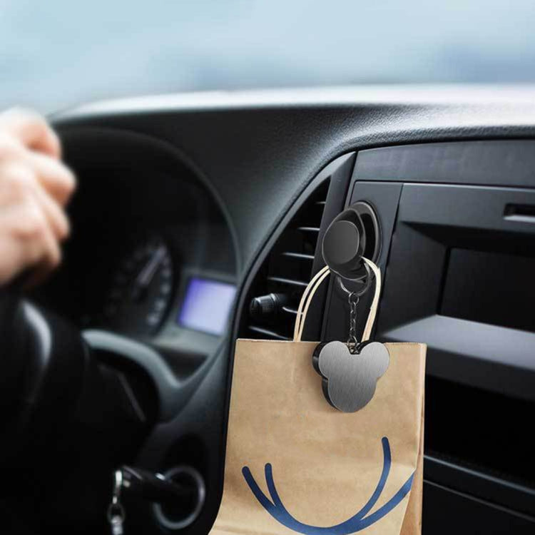 Glossy black car mini bag hanger hook holding a paper shopping bag on dashboard