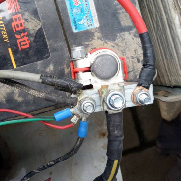 Car battery terminal clamp with red and black cable leads on battery top