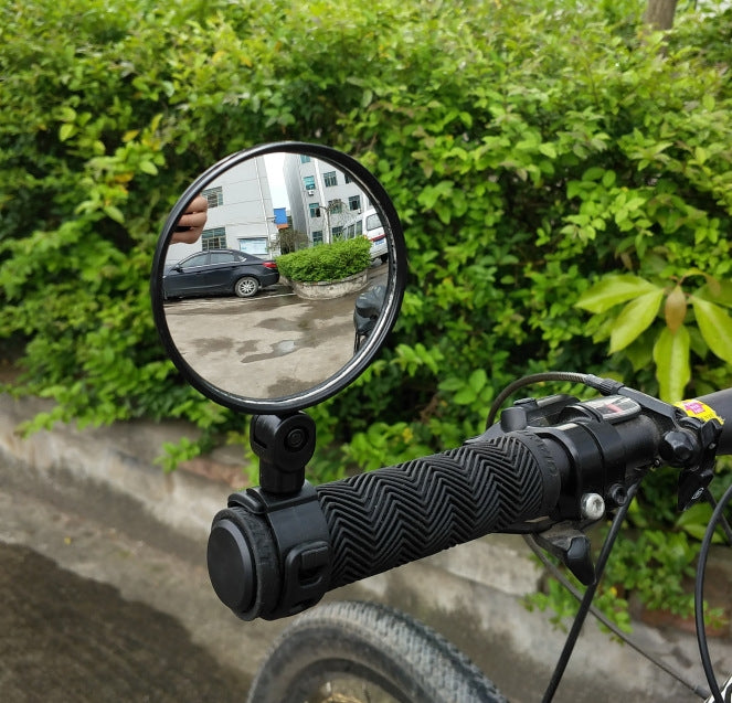 Bicycle rearview mirror with convex lens mounted on handlebar near the grips.