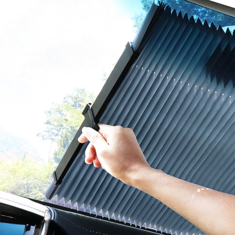 Hand pulling a retractable pleated sun shade cover attached to car windshield