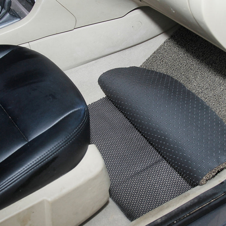 Black textured anti-slip mat placed on car floor next to seat, folded rectangular shape.