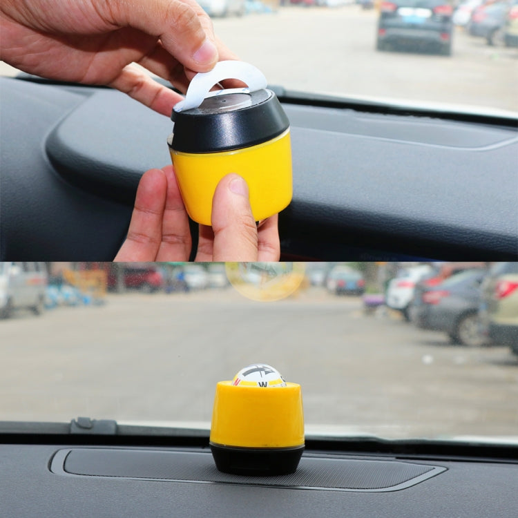 Hands placing a yellow car guidance compass on a car dashboard