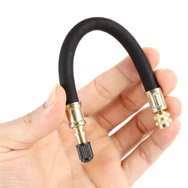 Black vacuum extension hoses with brass connectors held in hand, ribbed end caps