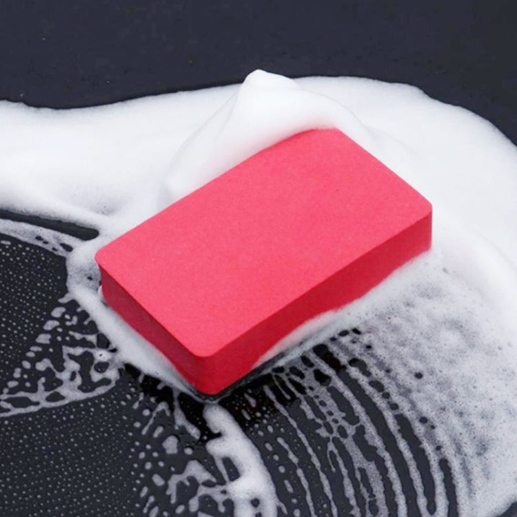 Red and dark gray car wash scrub sponge block on soapy water foam.