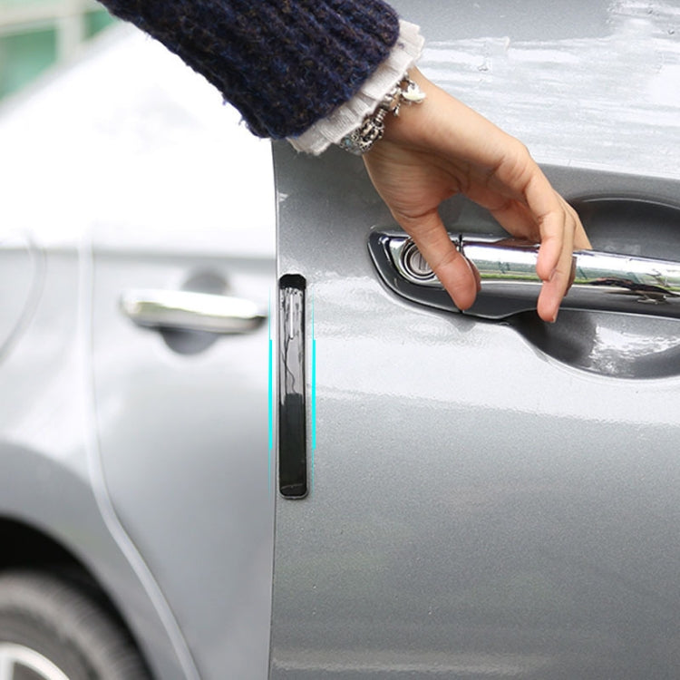 Hand applying anti-collision door strip sticker to car door edge near handle