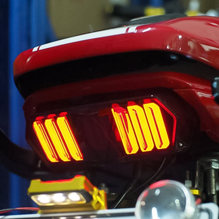 Motorcycle tail light brake lamp installed on rear, glowing red brake/amber turn lights