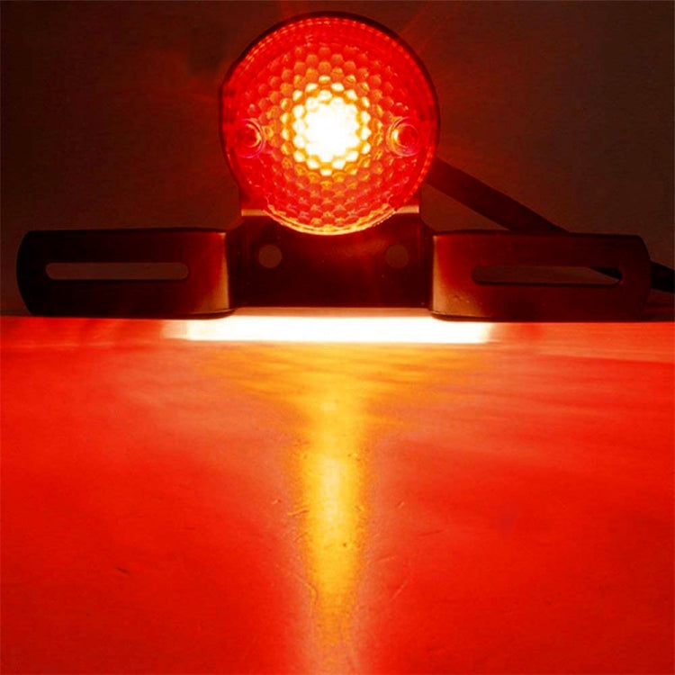 Lit retro round motorcycle brake light with red lens on a black bracket