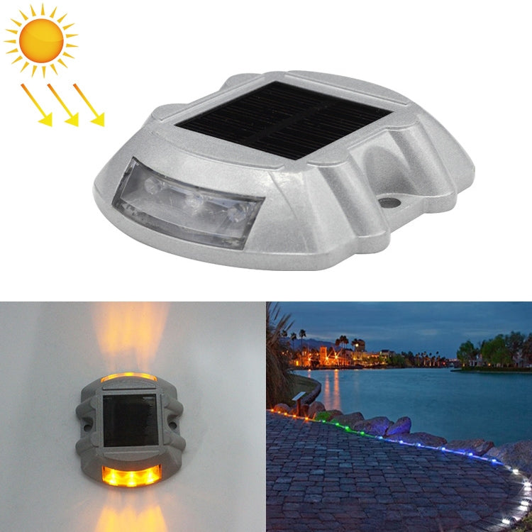 Solar road stud light with amber LED glow, clear lens housing, horseshoe shape.