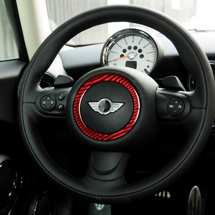 Steering wheel with red carbon-fiber ring sticker on center hub, round trim surround.