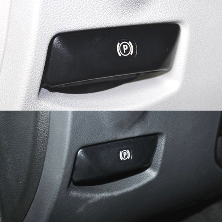 Black parking brake release button with P icon on car interior trim, close-up