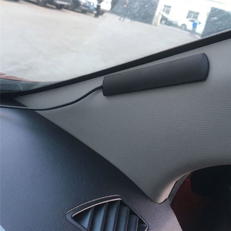 Black antenna amplifier mounted on car interior dash with cable