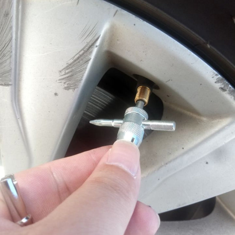 Tire valve core remover held against motorcycle tire valve inside wheel rim
