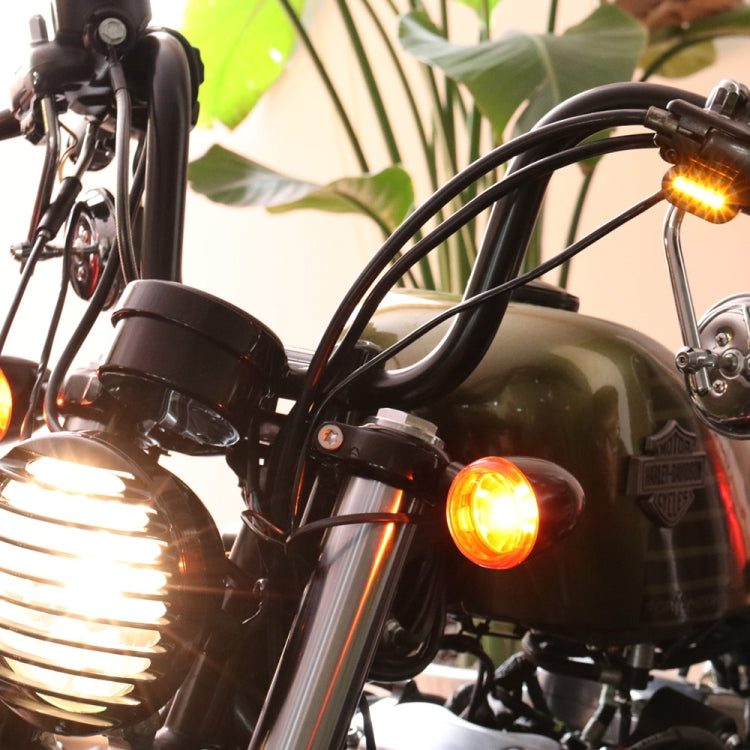 Motorcycle LED turn signal mirror light with amber glow near the handlebar.