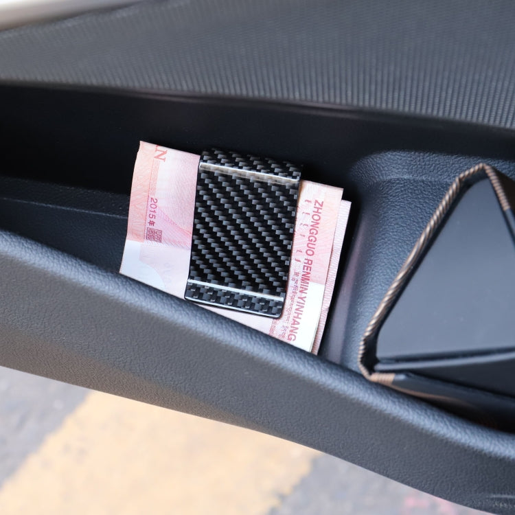Black carbon fiber card holder with cards inserted, dark dashboard close-up