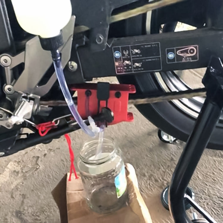 Motorcycle chain cleaning setup with clear bottle, hose, and mounted tool