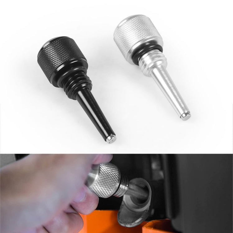 Pair of magnetic oil dipsticks—black and silver—one shown being inserted
