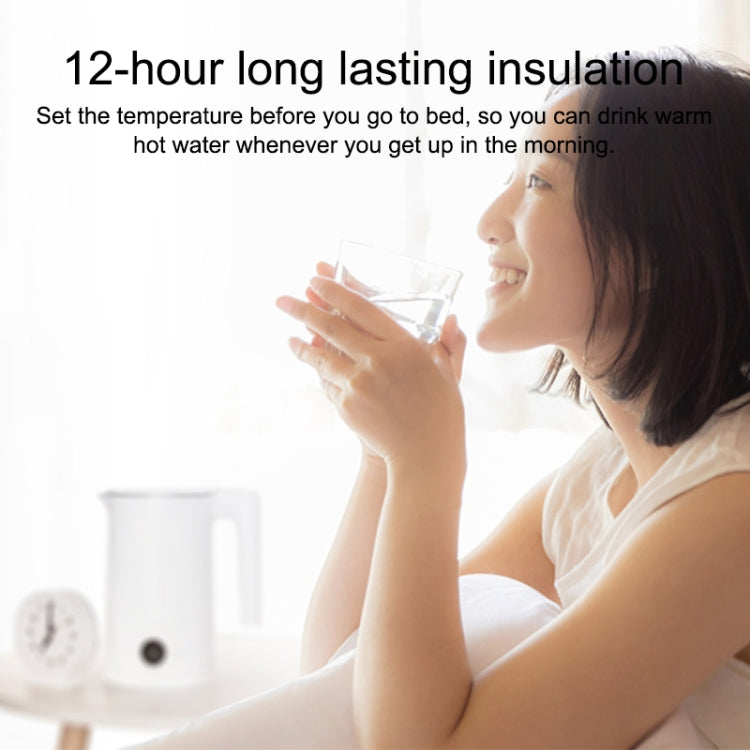 White electric kettle on countertop next to a person sipping from a glass