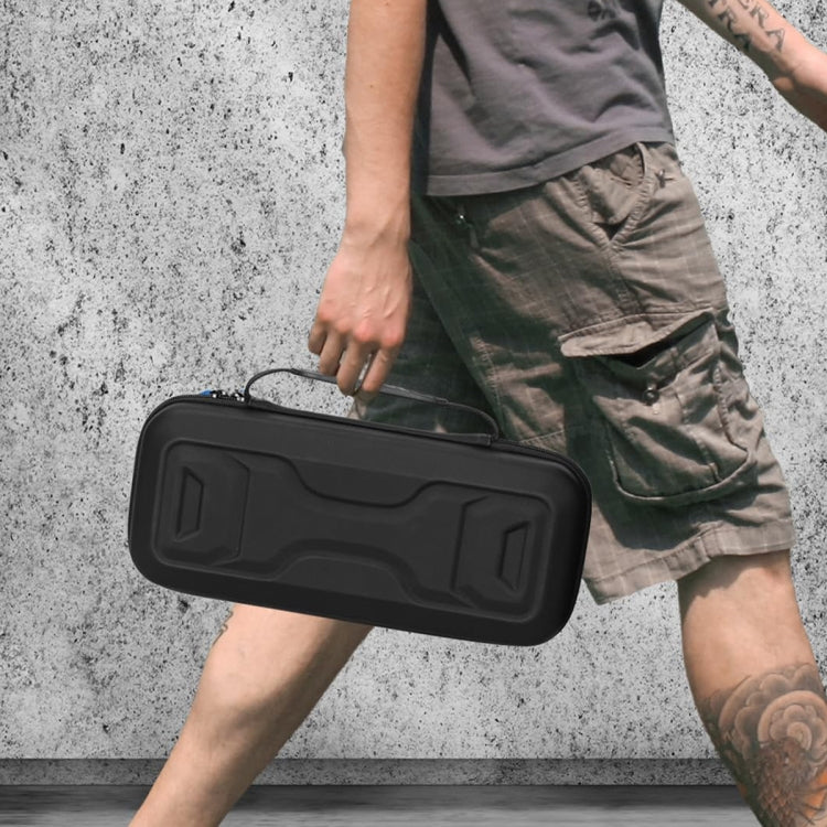 Black portable storage bag with handle, carried in front of a person