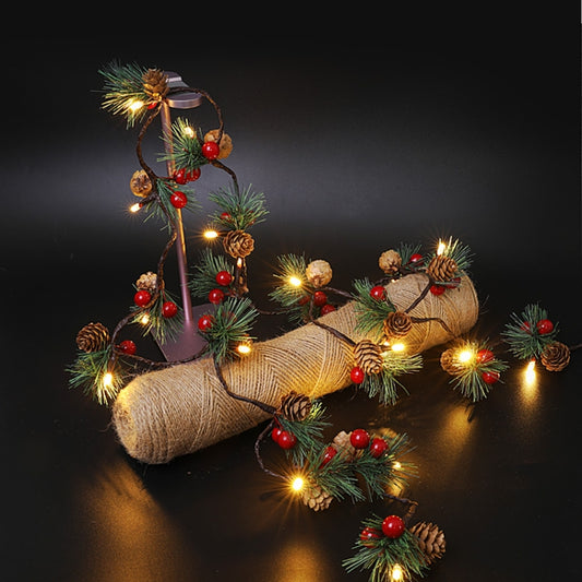 Christmas light string with pine needles, red berries, pine cones and warm bulbs