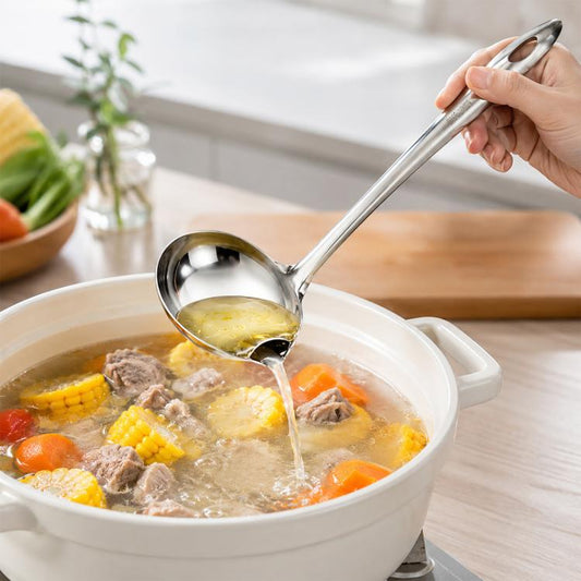 Stainless steel oil separating ladle held over a pot of soup with meat and vegetables