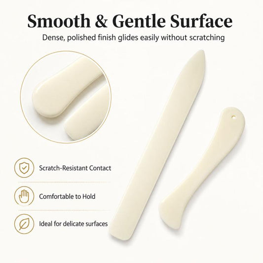 Two bone-colored bone-folding tools with smooth, rounded edges for creasing