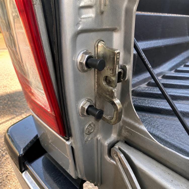 Tailgate lock bolt set installed on vehicle tailgate latch with two black knobs