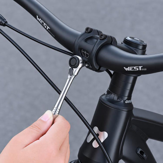 Bike ratchet wrench with screwdriver bit attached near handlebar clamp