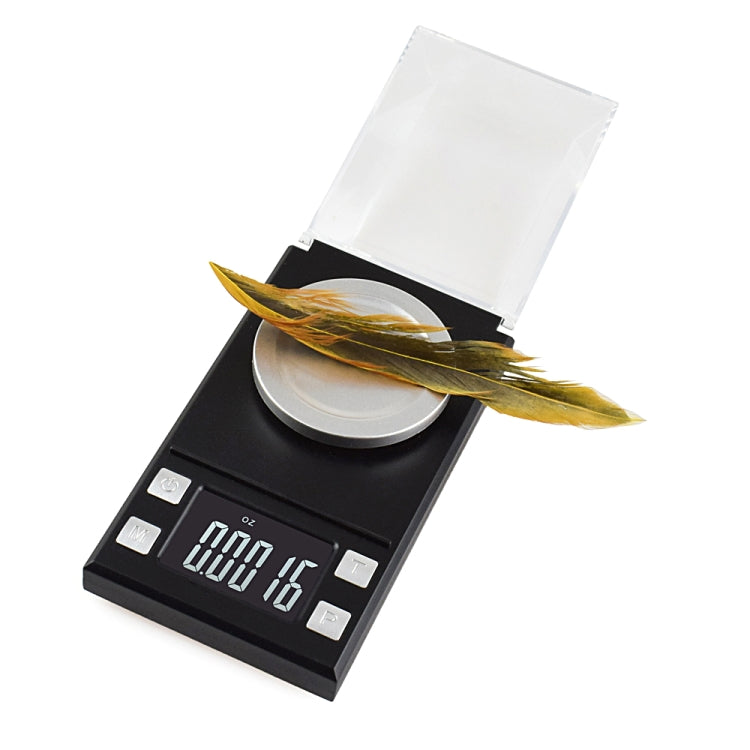 Digital jewelry scale with clear cover and round plate, feather resting on the platform