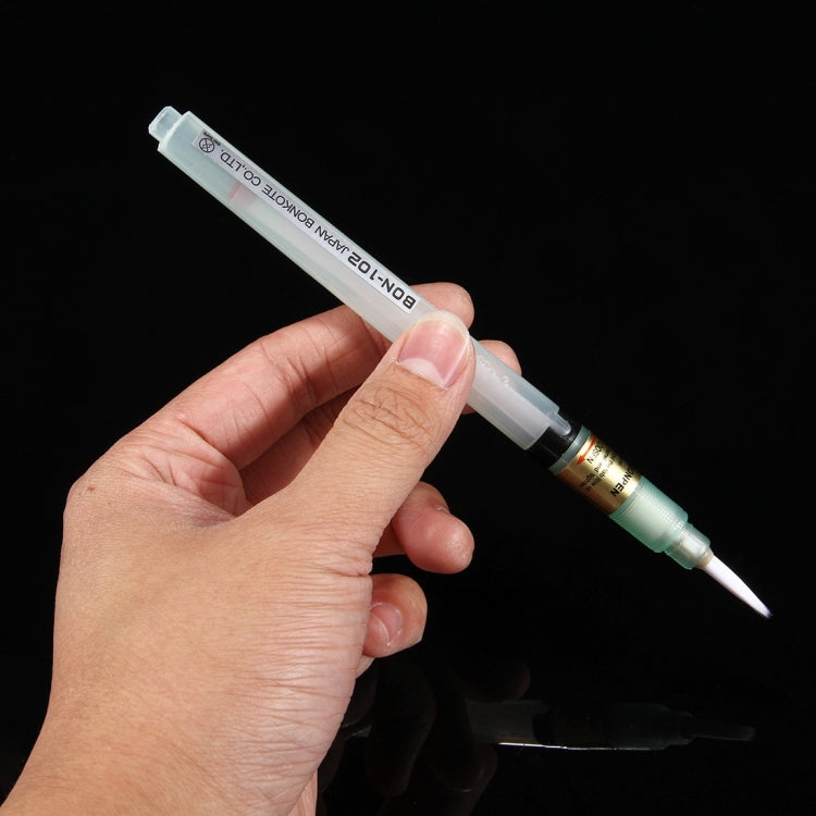 Flux pen in hand with mint body and white brush applicator tip